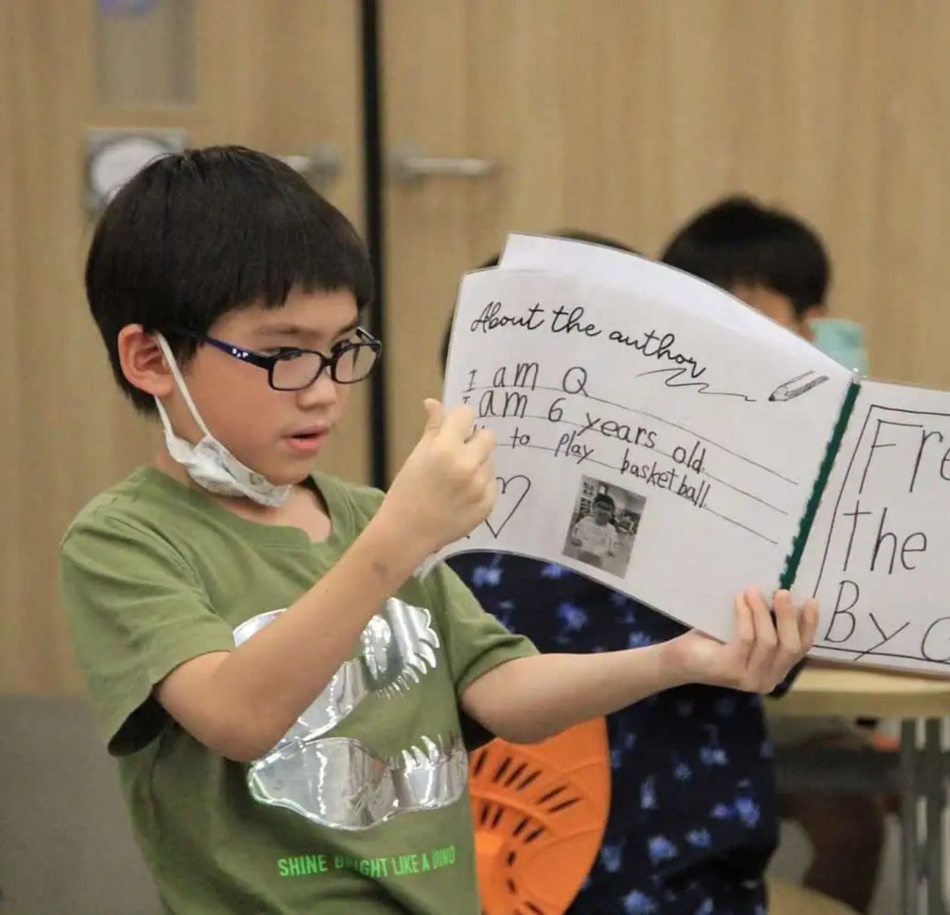 A young student reading his own story aloud in class