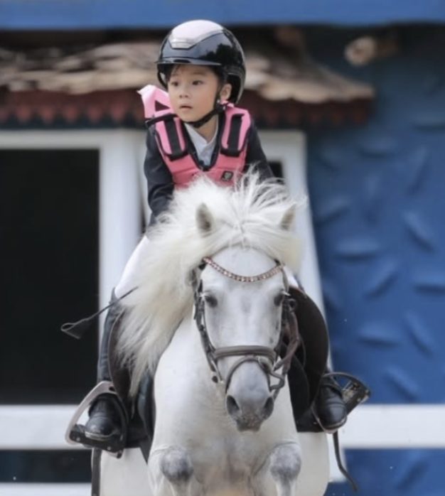 Student riding a white pony at an equestrian event