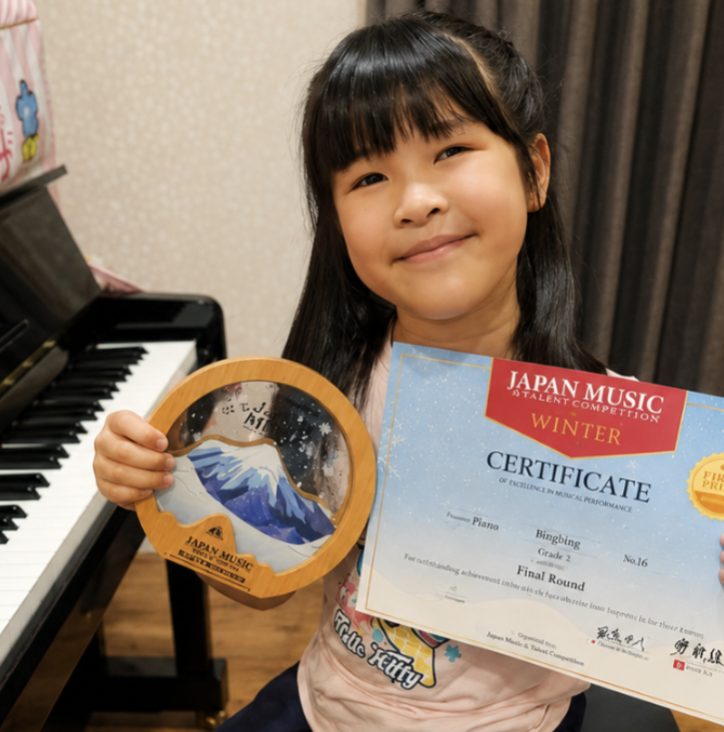 Student holding a music competition certificate and trophy