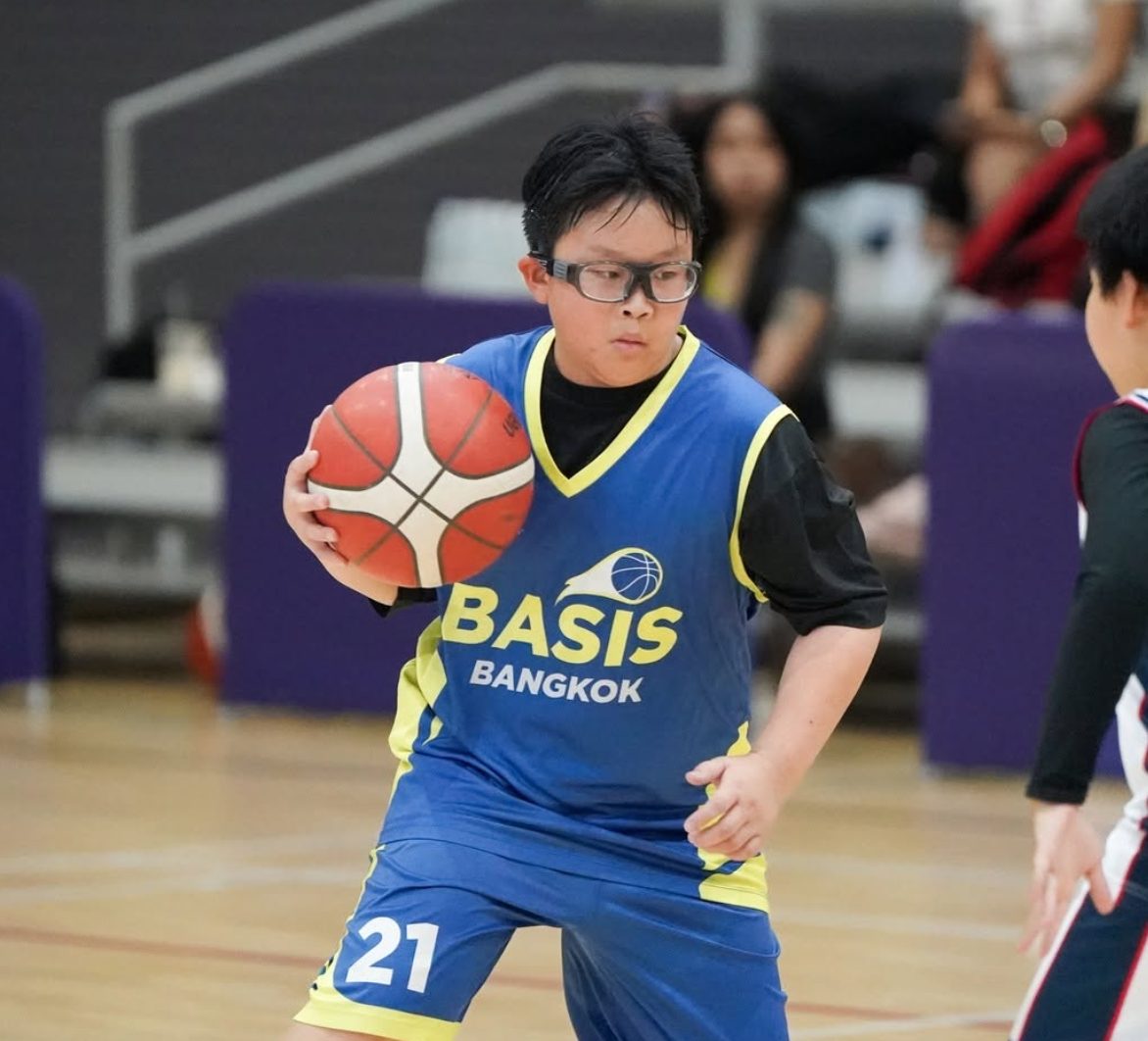 A BASIS Bangkok student dribbling a basketball during a game